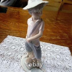 Lladró (Nao) porcelain sculpture of a boy playing slingshot, wearing a straw ha