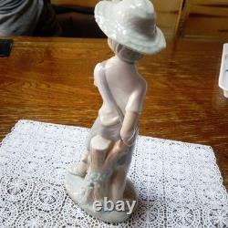 Lladró (Nao) porcelain sculpture of a boy playing slingshot, wearing a straw ha