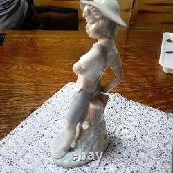 Lladró (Nao) porcelain sculpture of a boy playing slingshot, wearing a straw ha