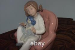 Nao By Lladro 15 CM Pig Tail Girl Sitting In A Pink Armchair Playing With A Doll