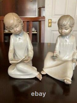 Two Nao (Lladro) figures both seated, girl reading a book and boy holding a ca